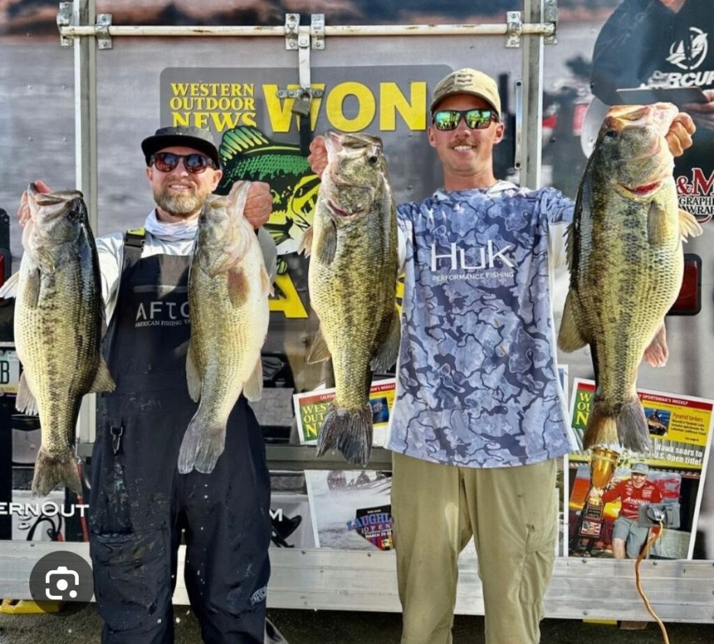 Two men holding large bass at a fishing event