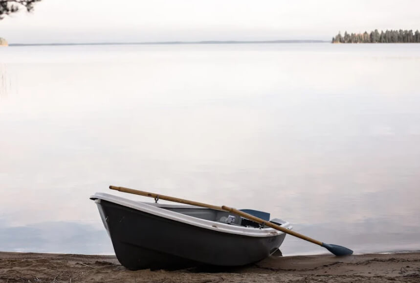 Small boat pulled onto the sand near still water
