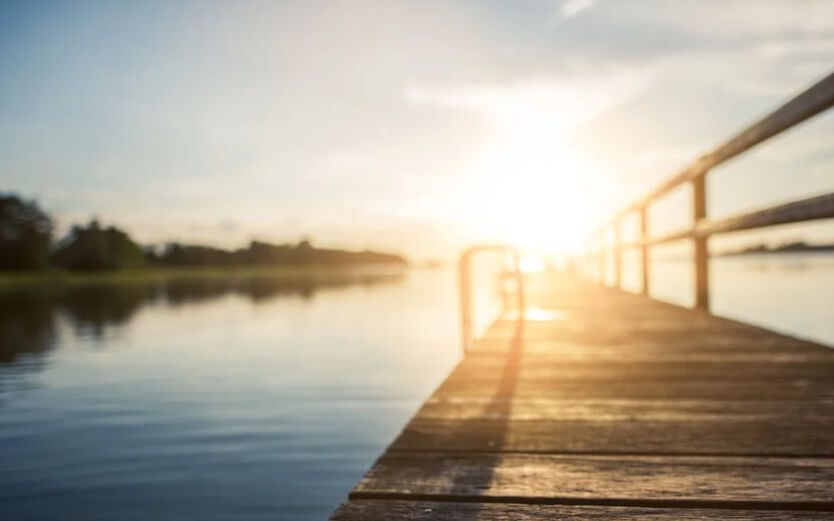 Wooden dock extending into a calm lake during sunrise