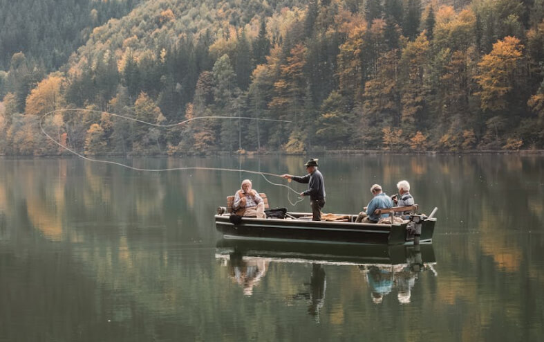 Four people fishing from a small boat on a calm forest lake