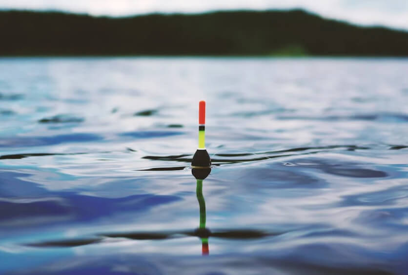 Close-up of a fishing bobber floating on calm lake water