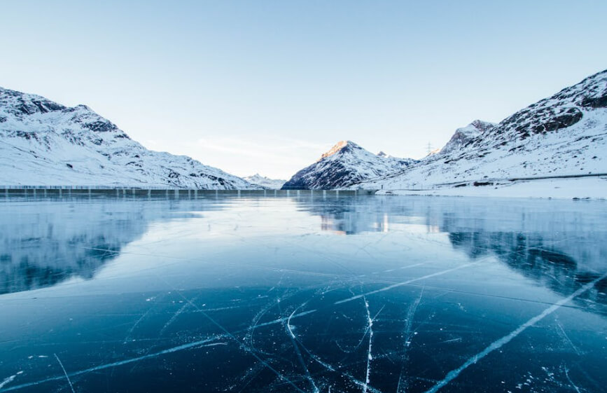 Icy surface reflecting mountains in a snowy valley