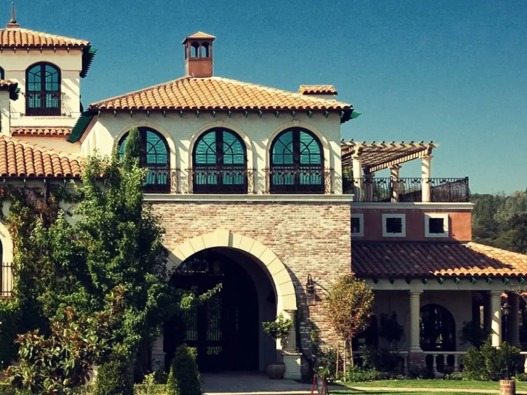 Large villa with arched entry, tall windows, and red-tiled roof